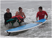 surfers and wheelchair in water image, operation amped nonprofit, ngo, charitable organization, landmark forum graduates making a difference